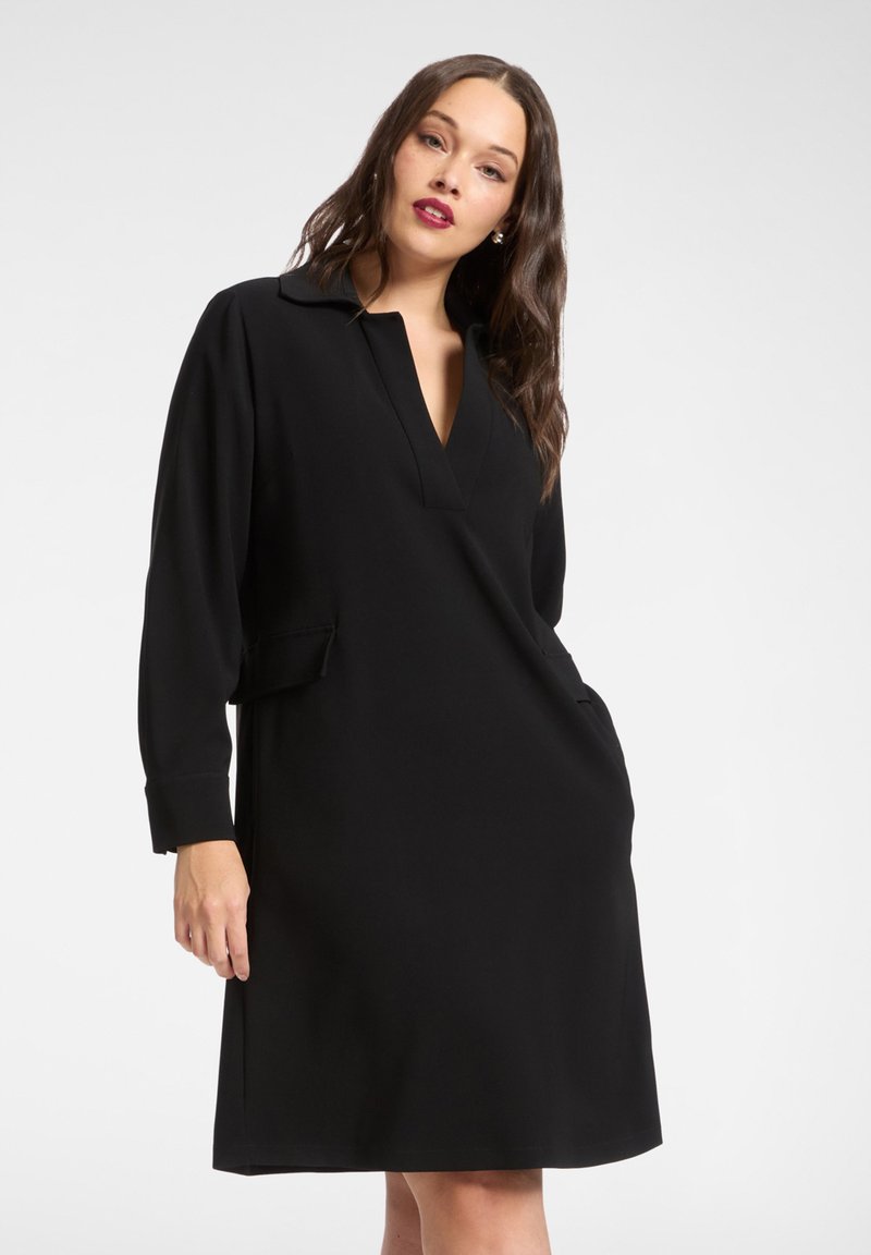 Abito nero con scollo a V, maniche lunghe e tasche laterali. Realizzato in tessuto liscio con vestibilità comoda e design minimalista.