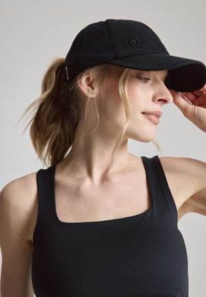 Casquette de baseball noire en tissu, avec une visière incurvée et un logo brodé à l'avant. Le modèle porte un débardeur noir.