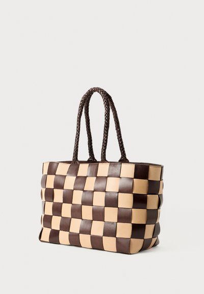 Brun og beige vævet læder tote taske med fletforhandle på en hvid baggrund, vinklet let til højre.