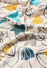 Bloemachtige stof met een crème achtergrond met blauwe, gele en grijze bloemen omrand door zwart, wat een vloeiende, gestructureerde uitstraling geeft.