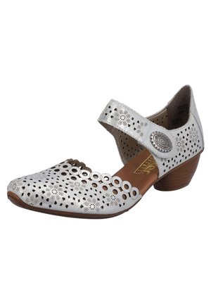 Des chaussures Mary Jane en cuir argenté avec des motifs floraux perforés, une large bride et un talon bas et contourné qui améliorent le confort et le style.