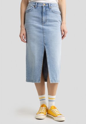 Light blue denim midi skirt with front slit, five pockets, and a button closure. Paired with yellow sneakers and striped socks.