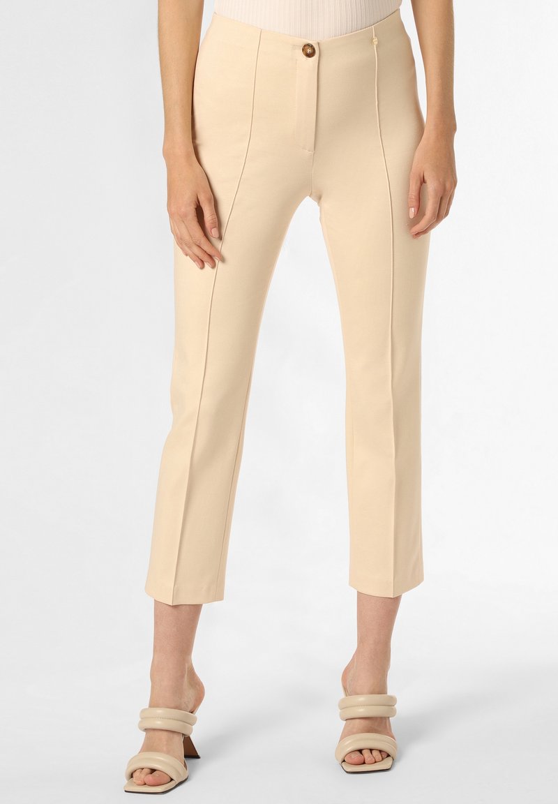 Beige maßgeschneiderte Hose mit schmaler Passform, ausgestattet mit vorderen Nahtdetails und einem Knopfverschluss. Kombiniert mit klobigen Absatzsandalen.