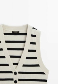 Gilet senza maniche in maglia a coste color crema con righe orizzontali nere, dotato di una profonda scollatura a V e due bottoni neri sul davanti.