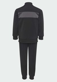 Ensemble de survêtement noir avec une veste zippée featuring une bande horizontale grise dans le dos, et un pantalon fuselé assorti. Fabriqué en tissu doux.