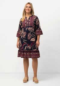 Robe marine à motif floral bordeaux et crème, avec un plastron boutonné, des manches trois-quarts et un ourlet en couches.
