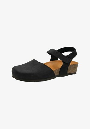 Sandalo nero con punta chiusa, cinturino regolabile alla caviglia, soletta imbottita color marrone chiaro e tacco a zeppa basso in sughero su sfondo bianco.
