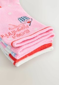 Vier Paar Socken gestapelt. Rosa mit weißen Punkten, rote Akzente; andere in Weiß und Blau mit Muster. Weiche, gestrickte Textur.