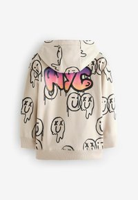 Sweat à capuche beige avec des visages souriants noirs dégoulinants et un grand texte coloré "NYC" dans le dos.