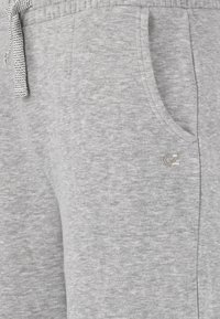 Grå sweatpants lavet af blødt, tekstureret stof. Har en elastisk waistband med en mønstret snor og en sidelomme. Diskret logoaccent.