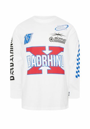 Camicia bianca a maniche lunghe con grande scritta rossa e blu "BADRHINO X", loghi a tema corse, numero 15 e motivo a scacchi blu sulla manica destra.