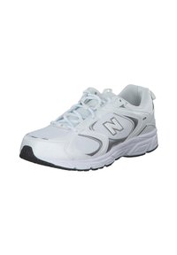 White athletic shoe with mesh and synthetic upper, reflective accents, decorative side contours, and a textured rubber sole.
