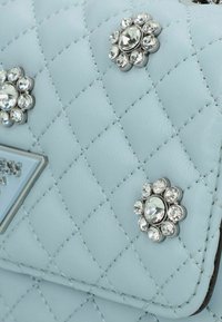 Borsa a tracolla trapuntata blu chiaro con hardware argentato e inserti decorativi a forma di fiore in cristallo. Texture in pelle liscia con cuciture a contrasto.