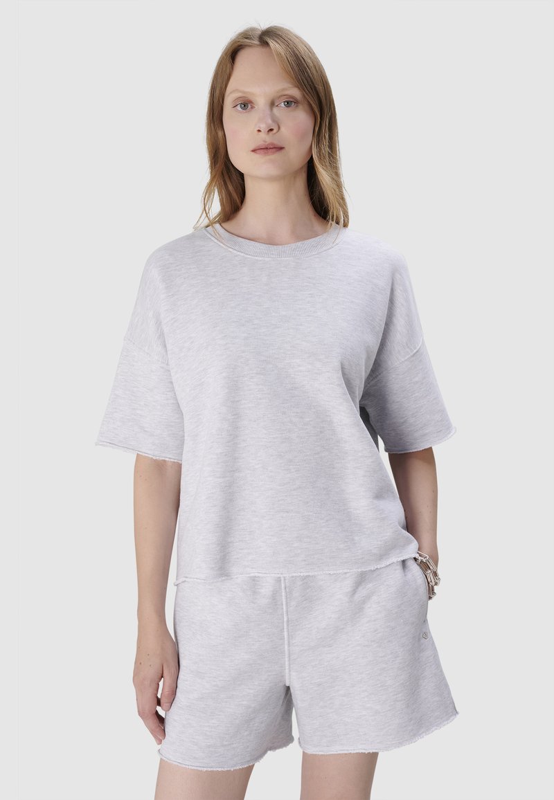 Jasnoszara, bawełniana, oversize t-shirt z krótkim rękawem i okrągłym dekoltem, zestawiona z pasującymi szarymi szortami o surowych krawędziach.