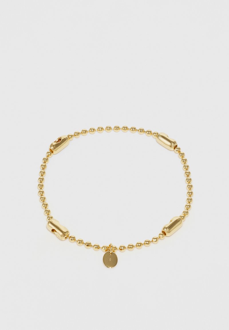 Auksinis apyrankės bruožas su sklandžiais ir tekstūruotais grandinėlėmis, suapvalinta pakabuku, visi eksponuoti prieš paprastą foną.