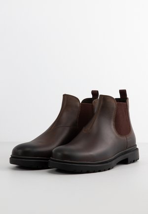 Stivali ankle in pelle marrone con pannelli laterali elasticizzati, punte arrotondate e suole in gomma nera. Texture liscia con discreti dettagli di cucitura.