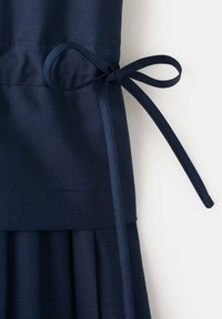 Vestito blu navy con corpetto aderente e gonna plissettata, dotato di una cintura annodata in vita realizzata con lo stesso tessuto, dalla texture liscia.