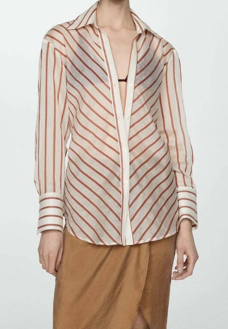 Camicia a maniche lunghe in tessuto trasparente con righe diagonali rosse e bianche, dotata di colletto classico e chiusura a bottoni, abbinata a una gonna marrone.