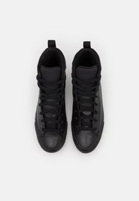 Black high-top sneakers with a smooth leather exterior, textured fabric tongue, and flat black laces. Rubber soles and rounded toe design.