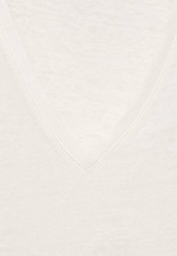 Hvid v-hals sweater lavet af et blødt, tekstureret stof. Har en dyb v-halsudskæring og et letvægts, åndbart design.