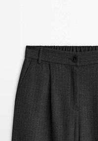 Pantalon gris foncé à fines rayures avec taille élastique, fermeture bouton noir, passants de ceinture et poches latérales.