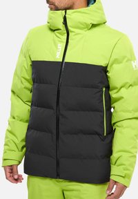 Grüne und schwarze, isolierte Jacke mit Vorderreißverschluss, puffigem Design, Kapuze und zwei Reißverschlusstaschen. Mit Logo auf der Brust und dem Ärmel.