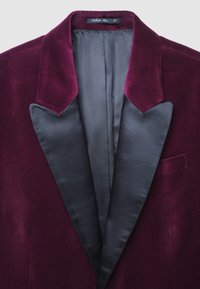 Dunkelvioletter Samtblazer für Herren mit schwarzen Satin-Revers und einem grauen Innenfutter, Größenetikett am Kragen sichtbar.