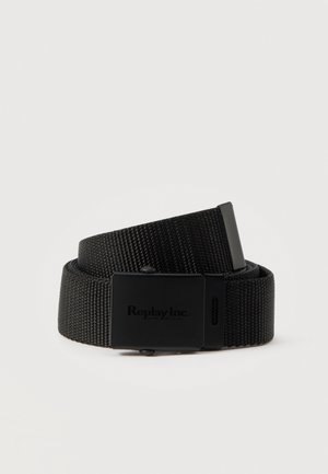 Cinturón Replay negro de tejido trenzado, enrollado sobre un fondo claro, con una hebilla rectangular negra y una punta metálica gris.