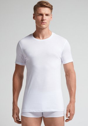 Weißes kurzärmeliges T-Shirt mit Rundhalsausschnitt, glatter Textur und eng anliegendem Design, getragen über passender weißer Unterwäsche.