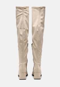 Botas de ante beige hasta la rodilla con un diseño ligeramente caído, que presentan cremalleras laterales negras y un tacón cuadrado.