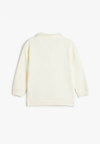 Sudadera color crema con mangas largas, escote redondeado y puños acanalados. Tejido suave con textura lisa, sin patrones visibles ni adornos.