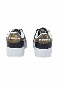 Scarpe sportive in bianco e nero con suole testurizzate, dotate di una patch sul tallone lucida e multicolore e logo del marchio sul retro.