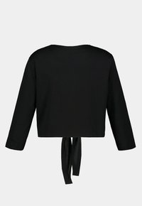 Haut noir à manches longues avec un col rond et un détail à nouer à l'arrière. Le tissu semble lisse avec un design à coupe régulière.