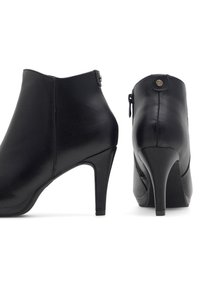 Czarne skórzane botki na kostkę z wysokim obcasem w szpic, gładką fakturą oraz zamek błyskawiczny z małym ozdobnym guzikiem.