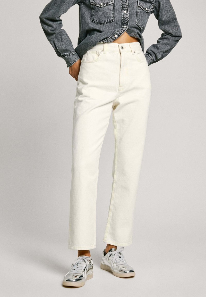 Vita denimjeans med rak benpassform, hög midja och femficksdesign. Kombinerad med en mörkgrå denimskjorta och metallicskor.