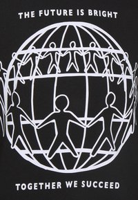 Czarna tkanina z białym nadrukiem graficznym przedstawiającym glob oraz postaci z kijami trzymające się za ręce, z tekstem: „PRZYSZŁOŚĆ JEST JASNA” oraz „RAZEM ODNIOSYMY SUKCES.”