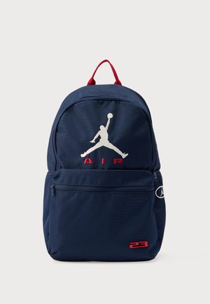 Tumesinine seljakott punaste detailidega, millel on valge tikandiga "Air" ja Jumpmani logo. Ees tõmblukuga tasku. Vastupidav kangas.