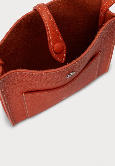 Červená kabelka z texturované kůže s uzávěrem na knoflík, viditelnými stehými a měkkým, semišovým vnitřkem. Kompaktní a strukturovaný design.