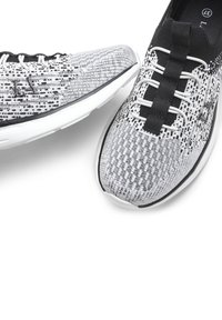 Juoda ir balta raštuota sportinė avalynė pasižymi lanksčia mezgimo viršutine dalimi, baltais raišteliais ir lengvu guminiais padu su apvaliu pirštu.