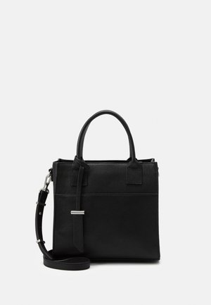 Bolso de mano de cuero negro con dos asas redondeadas, una correa de hombro ajustable y una etiqueta decorativa de cuero sobre un fondo blanco liso.