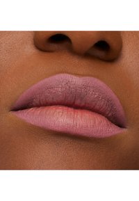 Rouge à lèvres rose mat sur des lèvres lisses et pulpeuses, avec un effet dégradé vers une teinte plus claire. Le teint est profond et complémentaire à la couleur des lèvres.