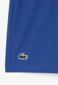 Polo shirt blu caratterizzato da un tessuto testurizzato, maniche corte e un logo di coccodrillo ricamato verde sull'orlo. Dettagli di cucitura puliti.