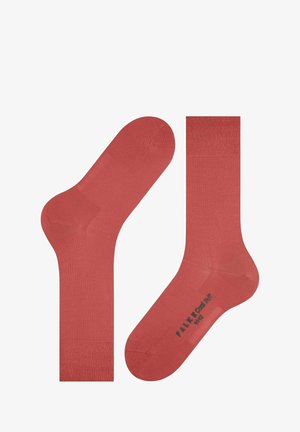 Chaussettes en coton corail avec une texture lisse, présentant un poignet côtelé et une marque estampillée sur la semelle. Design classique de longueur crew.