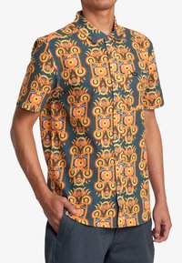 Camicia a maniche corte in un vivace motivo arancione e teal con design geometrici. Realizzata in tessuto liscio con colletto e bottoni.