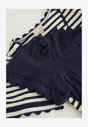 Two navy blue and white striped tops with scalloped edges, one solid navy and one striped, overlapping on a flat surface.