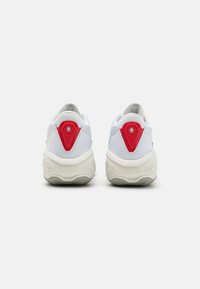 Zapatillas deportivas blancas con suela texturizada, con acentos rojos en el talón y un elemento de diseño hexagonal. Acolchadas con la inscripción "Fresh Foam".