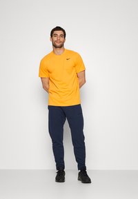 Nike Performance CREW SOLID - T-shirt desportiva - kumquat/black