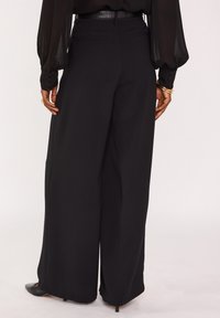 Zwarte broek met wijde pijpen van gladde stof, voorzien van een hoge taille, subtiele achterzakken en een nette afwerking aan de zoom.