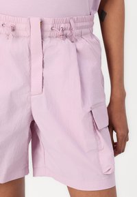 Helle rosa Cargo-Shorts aus strukturiertem Stoff, ausgestattet mit einem elastischen Bund, Kordelzug und seitlichen Taschen.