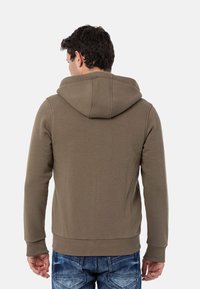Olijfgroene hooded sweatshirt, gemaakt van zachte stof. Heeft ribgebreide manchetten en zoom, met een losse pasvorm en minimale stikseldetails.